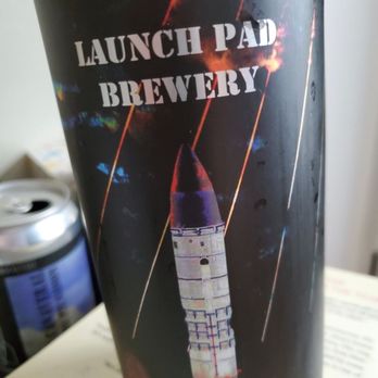 Launch Pad Brewery - Great looking can art! - The image shows a beverage can with space-themed artwork, including a rocket and streaks resembling fireworks or stars. The can displays the text "Launch Pad Brewery" prominently, along with a label indicating "2019 Bronze." The background is dark, emphasizing the space motif, and the can appears to be placed on a surface with some paper and other objects nearby. - Breweries Near Me - Aurora, Colorado