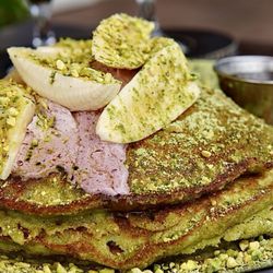 The Ravens Nest - Decadent banana Matcha pancakes with pistachios, raspberry sauce, and syrup