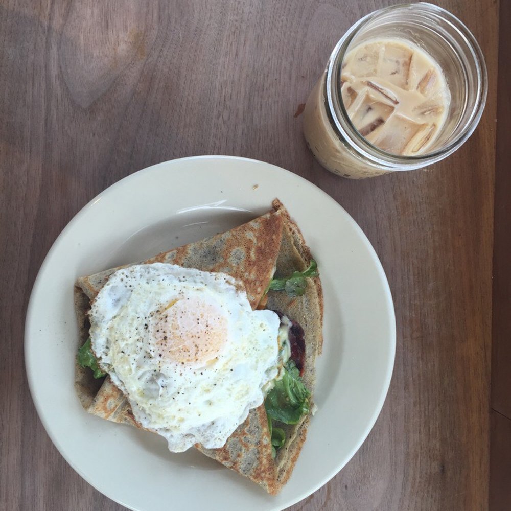 Bradbury's - Bacon, tomato, mixed greens savory crepe with a fried egg on top and an iced chai latte - Coffee & Tea Near Me - Madison, Wisconsin