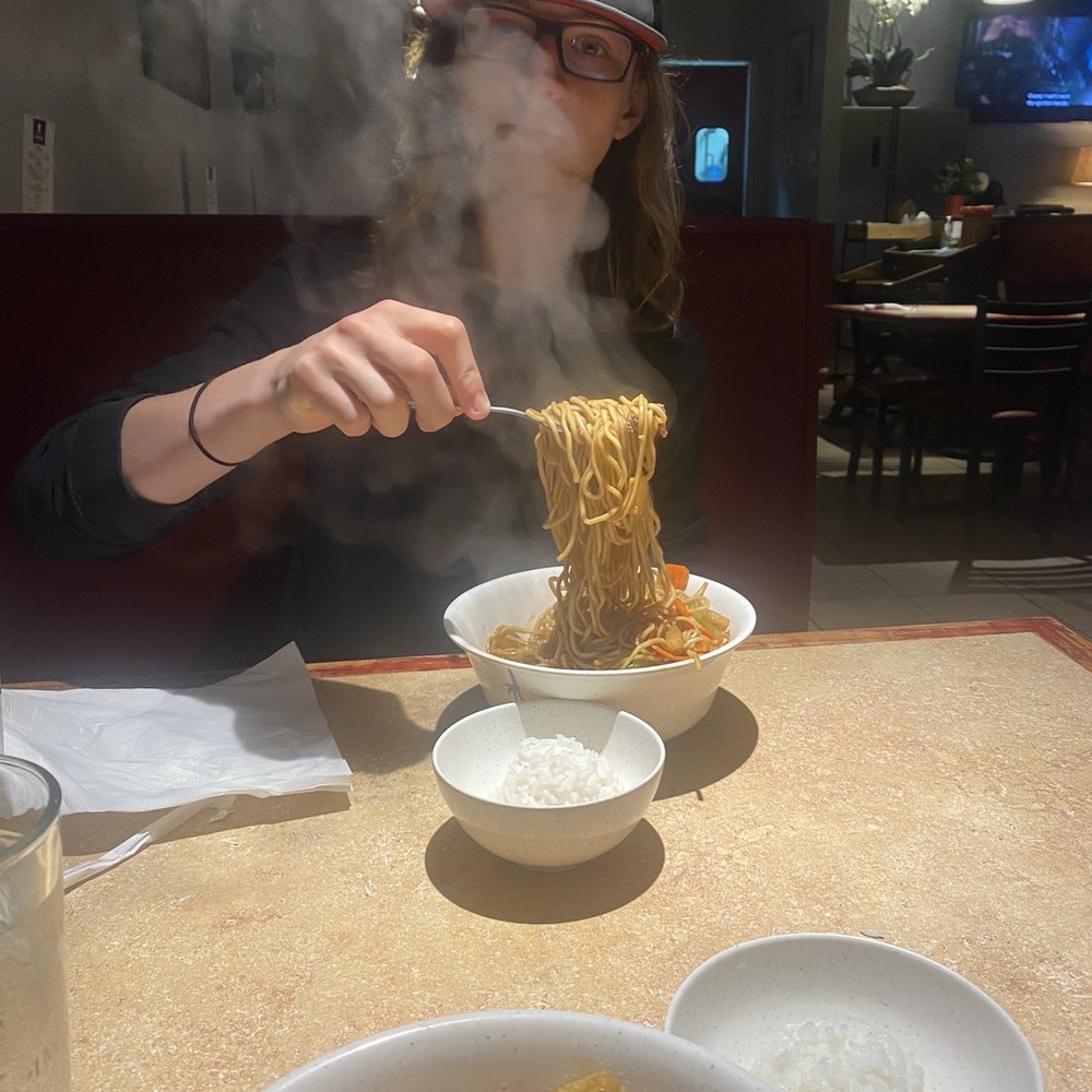 a woman eating noodles with chopsticks