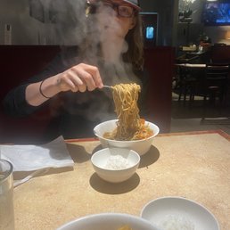 a woman eating noodles with chopsticks