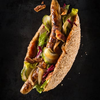 Holy Dogs - HOLY DOG #3 - J.C. SUPERSTAR: Bio-Bratwurst, Mischsalat, hausgemachte BBQ-Soße, Schmorzwiebeln, eingelegte Gurkenscheiben, Specksplitter - Food Trucks Near Me