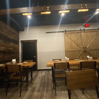 Mad For Chicken Plainview - inside seating - A dining area with wooden tables and chairs, wooden wall paneling, and a sliding barn door, inside a restaurant. - Coffee & Tea Near Me - Plainview, New York