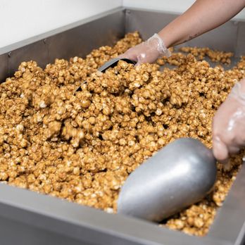 Garrett Popcorn Shops - a person scooping popcorn into a bin - Popcorn Shops Near Me - Chicago, Illinois