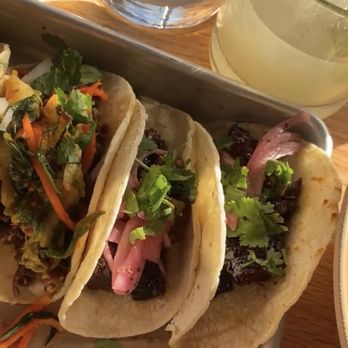 Bartaco Chastain Park - From left to right: sesame ribeye tacos (1), pork belly tacos (2). In background is a spicy marg. - Mexican Near Me - Atlanta, Georgia Bartaco Chastain Park - From left to right: sesame ribeye tacos (1), pork belly tacos (2). In background is a spicy marg. - Mexican Near Me - Atlanta, Georgia
