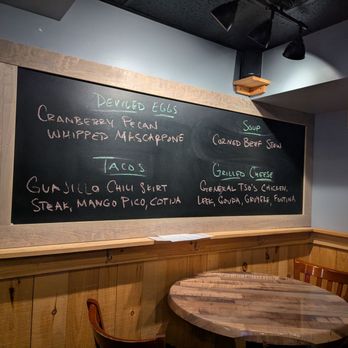 Backstage Pub - A chalkboard menu displays deviled eggs, tacos, and soup options in a restaurant setting, with wooden paneling and a small table nearby. - Burgers Near Me - Schenectady, New York