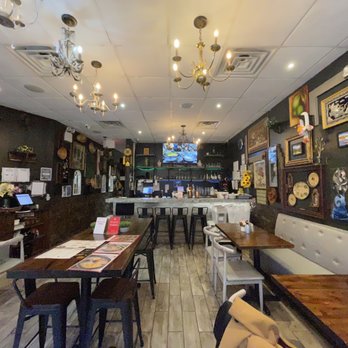Link Thai - Inside - A restaurant interior featuring dark walls, multiple chandeliers, framed artwork, and a bar area with stools. - Thai Near Me - Brooklyn, New York