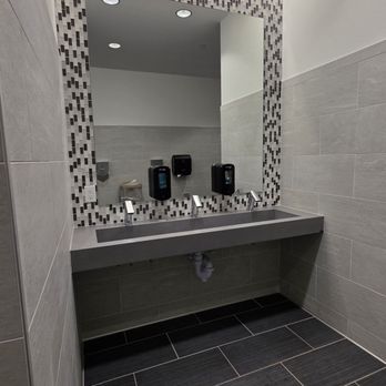 Living Spaces - 2nd floor restroom - A restroom features a double sink with a large mirror above, tiled walls, and dark tiled flooring, with soap dispensers mounted on the wall. - Home Decor Near Me - Lone Tree, Colorado