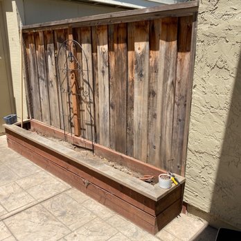 Rios Gardening - a wooden planter on a patio - Gardeners Near Me