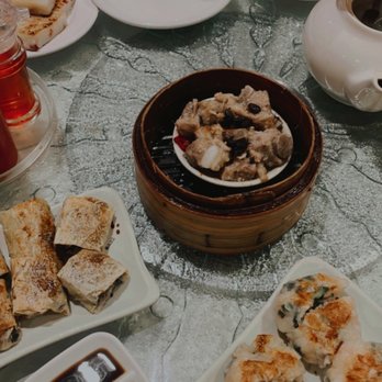 Dim Sum King - Different kinds of dim sum - A variety of dim sum dishes, including spring rolls, steamed buns, and fried rolls, are arranged on plates with dipping sauces on a table. - Dim Sum Near Me - Toronto, Ontario