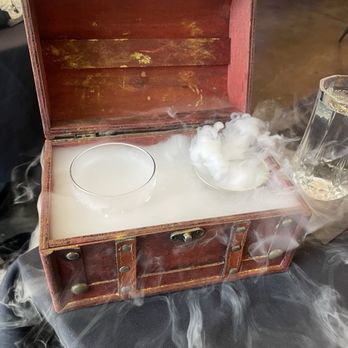 Deluxe Fun Dining - Irish Cream on the rocks served in a dry ice Treasure Chest Box - Bars Near Me - Charlotte, North Carolina Deluxe Fun Dining - Irish Cream on the rocks served in a dry ice Treasure Chest Box - Bars Near Me - Charlotte, North Carolina