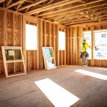 Builders FirstSource - A construction worker in a bright yellow safety shirt and hard hat stands inside the wooden frame of a house under constructi... - Building Supplies Near Me - Graham, Washington Builders FirstSource - A construction worker in a bright yellow safety shirt and hard hat stands inside the wooden frame of a house under constructi... - Building Supplies Near Me - Graham, Washington