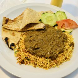 Persis Indian Grill - Goat over biryani with naan, tomato and cucumbers. Mango lassi as the beverage.