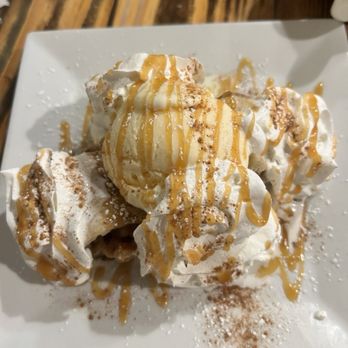 Checkers Old Munchen - A dessert featuring whipped cream, caramel drizzle, and cocoa powder on a white square plate, served at a restaurant. - American Near Me - Pompano Beach, Florida