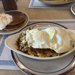 Dish with hash browns, peppers, mushrooms with an extra eggs. Pumpkin pancakes in back.