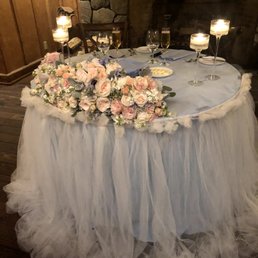 Sweetheart table with dusty blue linen and white tulle, candles, and re-purposed bouquets. Sweetheart table with dusty blue linen and white tulle, candles, and re-purposed bouquets.