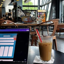 a glass of iced coffee next to a laptop