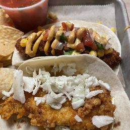 Fried fish taco and Nashville hot taco with a side of chips and salsa Fried fish taco and Nashville hot taco with a side of chips and salsa
