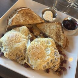 Corned beef hash with two over easy eggs and a side of sourdough toast with butter and blackberry jam