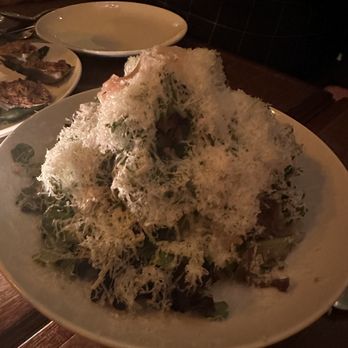 Swoony's - Mixed greens - A large bowl of salad with shredded cheese and herbs on top, served in a restaurant setting with dim lighting. - New American Near Me - Brooklyn, New York
