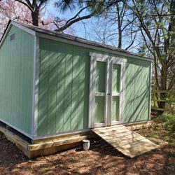 Quaker Sheds - 12x8x9 A frame with a wood ramp on a gravel pad