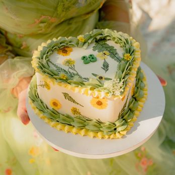 Bells Cake House - a woman holding a heart shaped cake - Custom Cakes Near Me - Orlando, Florida