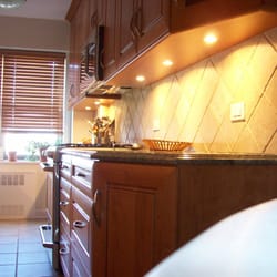 Designer Kitchen & Bath of New York - Custom bottom panels incorporating a light rail molding, a finished panel and recessed lights for a beautifully sleek finished bottom look.