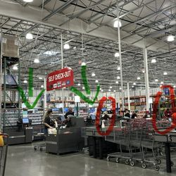 Costco Wholesale - At least 3 available self checkout machines (see green arrows) but 2 Costco employees are holding up the line (see red circles).