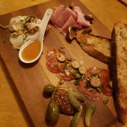 a cutting board with bread, pickles, and meat