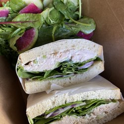 Ki Coffee - Chicken Salad Sandwich: Chicken Salad, Spinach, Red Onion, on Sourdough Bread. Accompanied by a side salad.