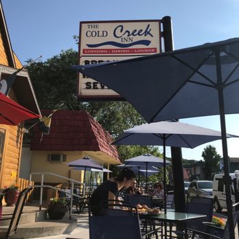 Cold Creek Inn Restaurant - Outdoor seating along Benzie blvd. Umbrellas to give you some protection from the evening sun. - American Near Me - Beulah, Michigan Cold Creek Inn Restaurant - Outdoor seating along Benzie blvd. Umbrellas to give you some protection from the evening sun. - American Near Me - Beulah, Michigan