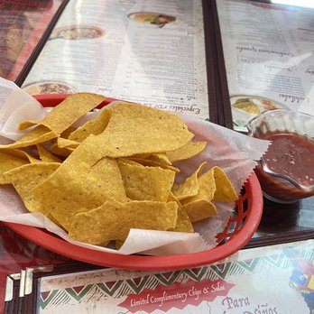 El Tequila - Lunch Steak fajita - A basket of tortilla chips with a side of salsa is placed on a restaurant table with menus in the background. - Mexican Near Me - Northfield, Minnesota