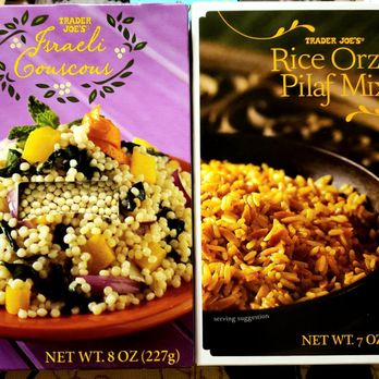 Trader Joe's - Can't Wait To Try These!! - The image features two Trader Joe's product boxes placed side by side. The left box is for Israeli couscous, with a purple background and an image of a prepared couscous dish topped with vegetables. The right box is for rice pilaf mix, with a black background and an image of cooked rice in a bowl. Both boxes display product names, weight information, and serving suggestions, with the couscous box weighing 8 oz and the rice pilaf box weighing 7 oz. - Grocery Near Me - Millburn, New Jersey