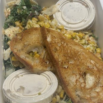 Corn On The Corner - Kale Caesar salad - A kale Caesar salad with corn, shredded chicken, and fried bread pieces, served with two small containers of dressing. - Food Trucks Near Me - Dearborn, Michigan
