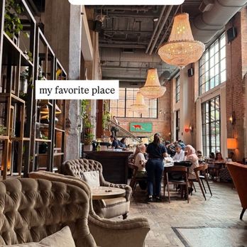 The Allis - Ambiance - A spacious restaurant interior at The Allis in Chicago features high ceilings, large windows, chandeliers, and patrons dining at tables. - Lounges Near Me - Chicago, Illinois