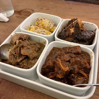 Stella's - Curry Goat (bottom left), Oxtail (bottom right), Jerk Chicken, Corn - Caribbean Near Me - Brooklyn, New York Stella's - Curry Goat (bottom left), Oxtail (bottom right), Jerk Chicken, Corn - Caribbean Near Me - Brooklyn, New York