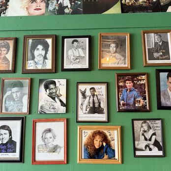 Circular Lounge - Can't beat the celebrity wall! - A collection of framed celebrity photographs and autographs is displayed on a green wall. The frames vary in color, including black, gold, and wood tones. The images include both black-and-white and color photographs of various celebrities, some with handwritten signatures and messages. The arrangement appears organized, with multiple rows and columns, creating a gallery-like display. - Lounges Near Me - Denver, Colorado