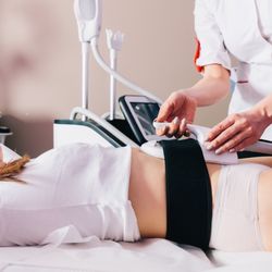 Comprehensive Medical Weight Loss - A healthcare professional performs a non-invasive body contouring or weight loss treatment on a patient lying comfortably in ...