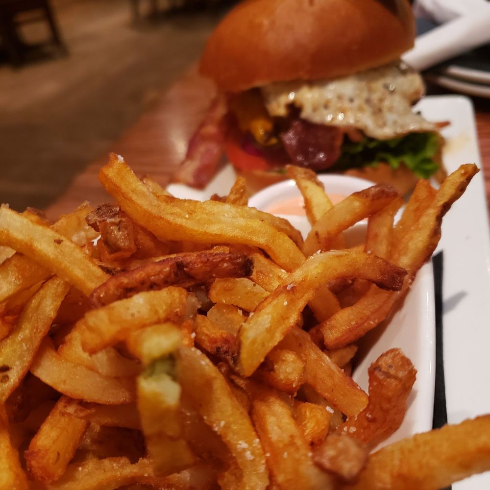 Kenzington Burger Bar - Side of fries with the kenzy burger in the background - Burgers Near Me - Orillia, Ontario Kenzington Burger Bar - Side of fries with the kenzy burger in the background - Burgers Near Me - Orillia, Ontario