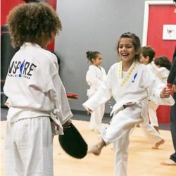 Inspire Martial Arts & Fitness - Practicing a kick with a partner and a handheld target.