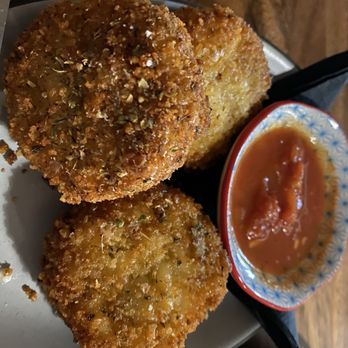 The Side Bar - Mac and cheese bites - Three fried mac and cheese bites with a crispy coating are served on a plate with a small bowl of dipping sauce, likely at a bar or casual dining setting. - Vegetarian Near Me - Doylestown, Pennsylvania
