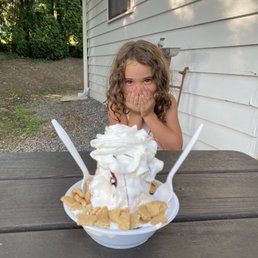 a little girl sitting at a table with a bowl of ice cream and whipped cream a little girl sitting at a table with a bowl of ice cream and whipped cream