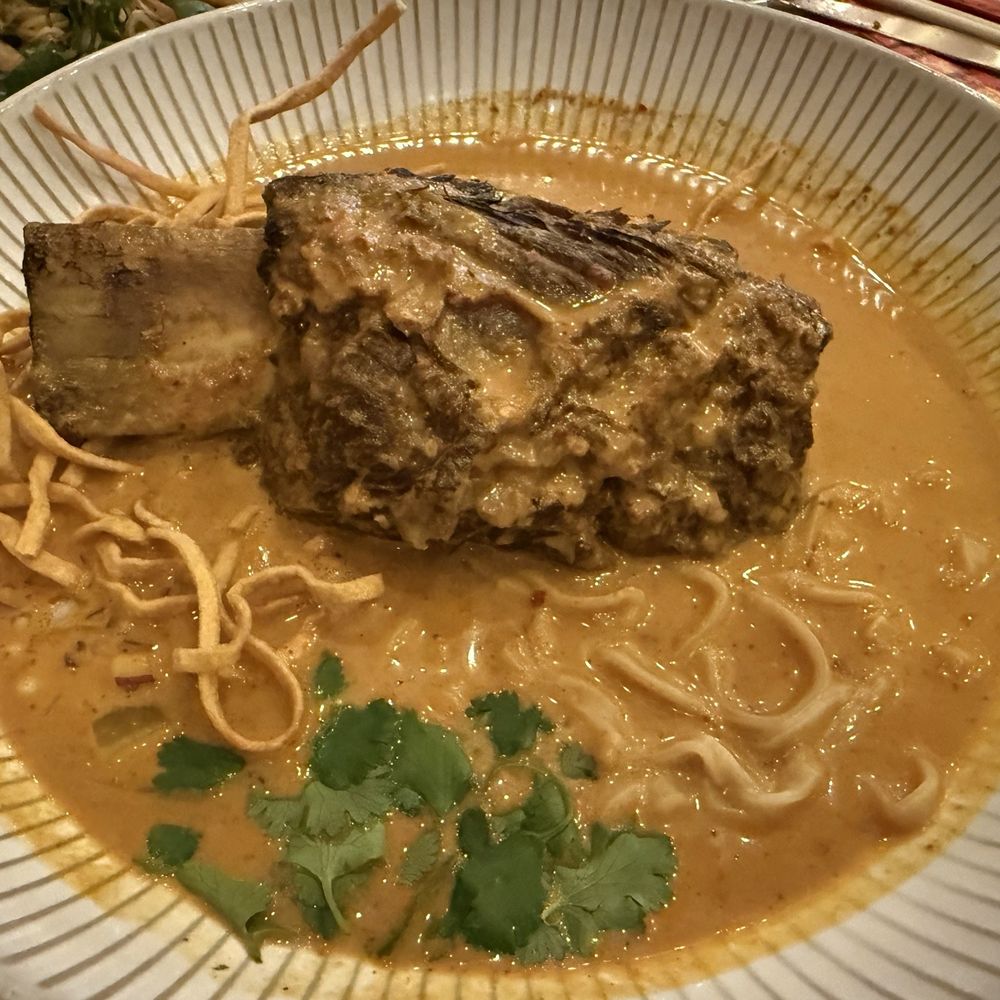 Thaihey Nola - Khao Soi Short Rib  Slow cooked Short Rib Northern style yellow curry noodle soup with fried egg noodles, pickled radish, and fresh cilantro - Thai Near Me - New Orleans, Louisiana