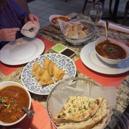 Chicken vindaloo, one order of butter chicken (top, far corner of the table), vegetable samosas, garlic naan, and plain naan. Chicken vindaloo, one order of butter chicken (top, far corner of the table), vegetable samosas, garlic naan, and plain naan.