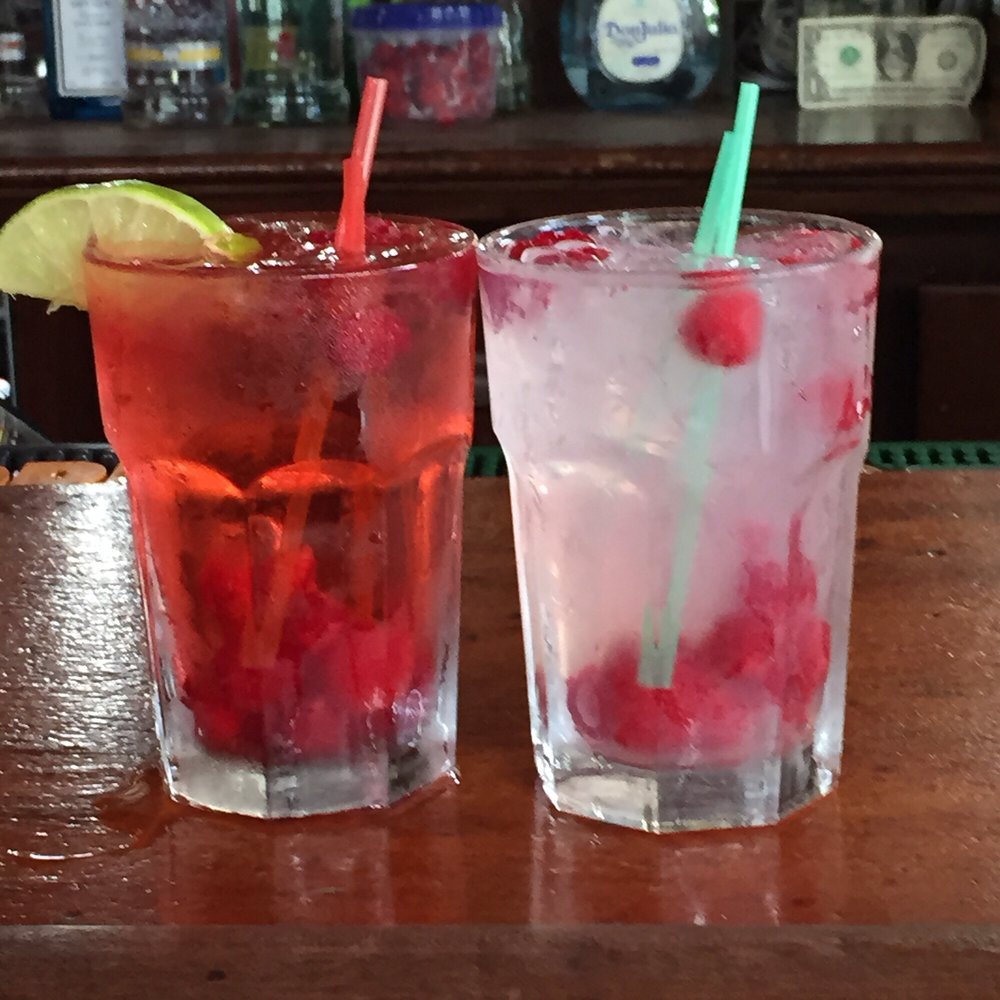 two glasses of drinks on a bar two glasses of drinks on a bar