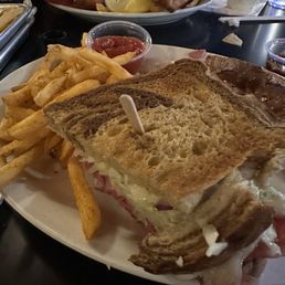 Half of the reuben sandwich and the fish and chips in the background. Half of the reuben sandwich and the fish and chips in the background.