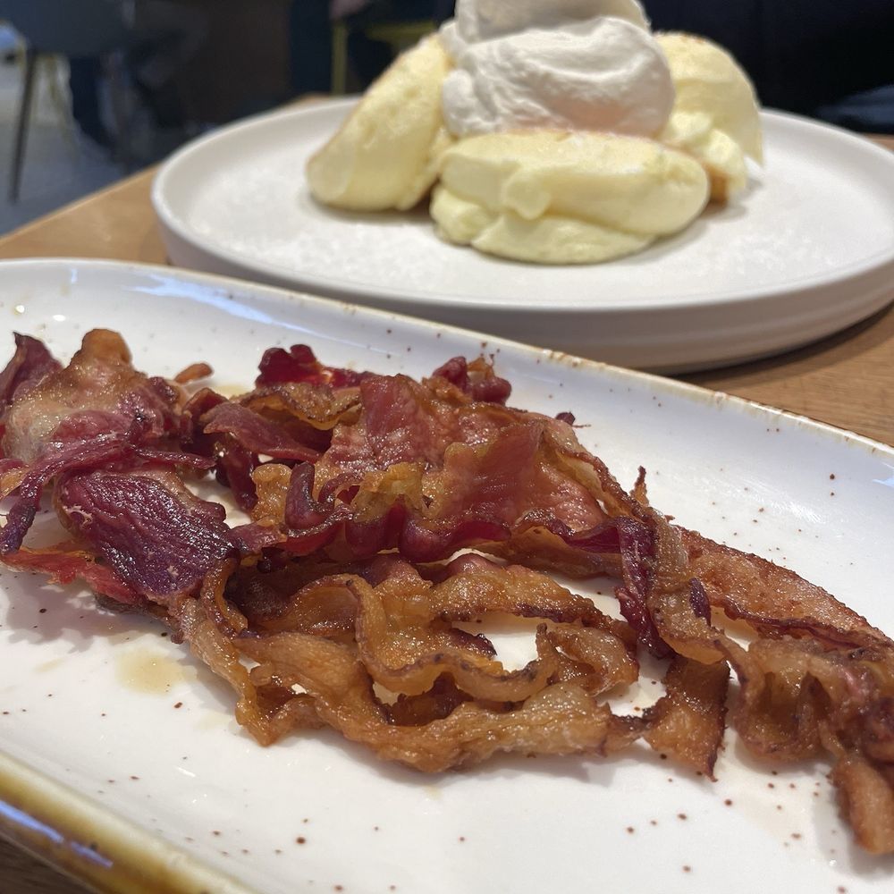 Flipper’s - Order of bacon with Flipper's soufflé pancakes in background - Pancakes Near Me - New York, New York Flipper’s - Order of bacon with Flipper's soufflé pancakes in background - Pancakes Near Me - New York, New York