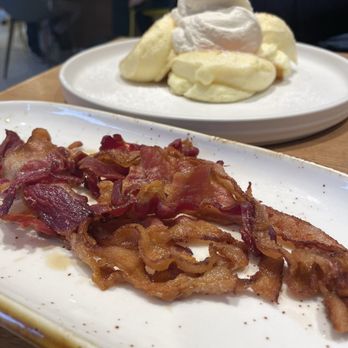 Flipper’s - Order of bacon with Flipper's soufflé pancakes in background - Pancakes Near Me - New York, New York Flipper’s - Order of bacon with Flipper's soufflé pancakes in background - Pancakes Near Me - New York, New York