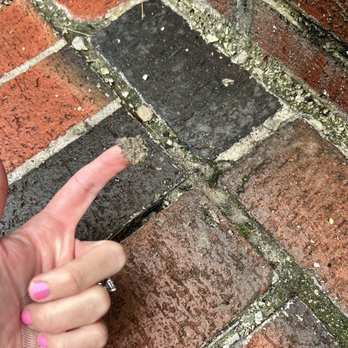 López Construction - Stairs - A hand with pink nail polish points at a cracked and uneven brick sidewalk with dirt and debris. - Masonry/Concrete Near Me