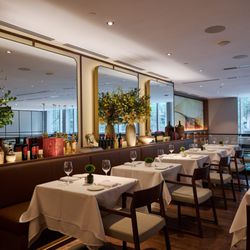 Felice Brickell - The main dining area of an Italian restaurant featuring brown leather banquettes, crisp white linens, and large mirrors refle...